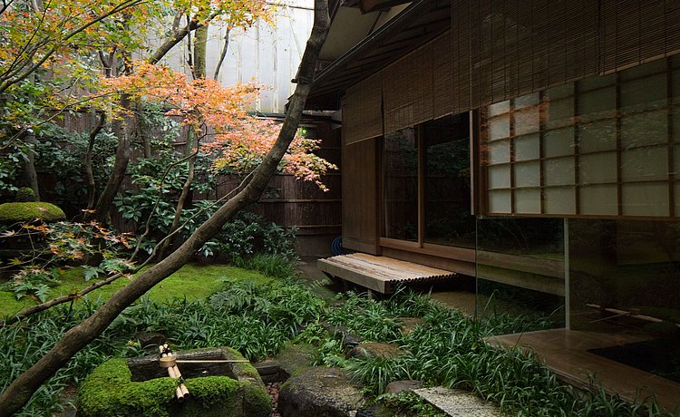 Blick vom zentralen Lichthof auf eine Treppenstufe vor der geöffneten Schiebetür, die in das Tawaraya Ryokan führt